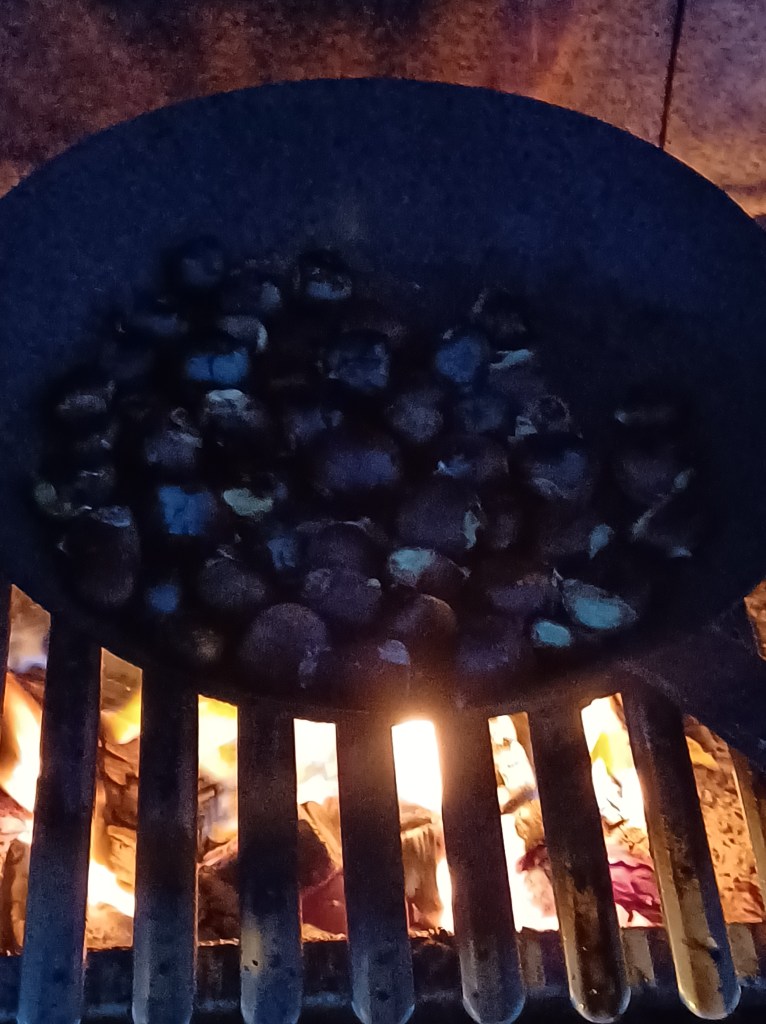 castañas without the needle covered shell roasting on a flame.